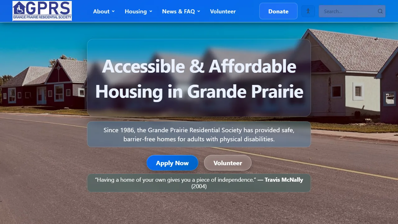 The society's home page: a row of single-storey houses along a street, under the heading Accessible and Affordable Housing in Grande Prairie, with Apply Now and Volunteer buttons.